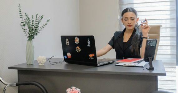 Woman working at desk with laptop and phone, illustrating virtual PBX adoption