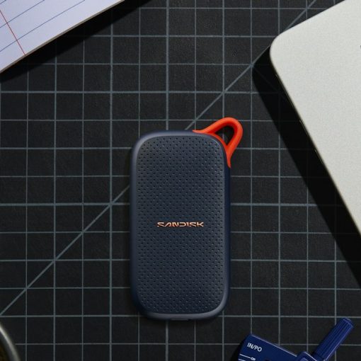 Portable SSD, coffee, and stationery on a grid mat, illustrating backing up virtual machines