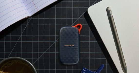 Portable SSD, coffee, and stationery on a grid mat, illustrating backing up virtual machines