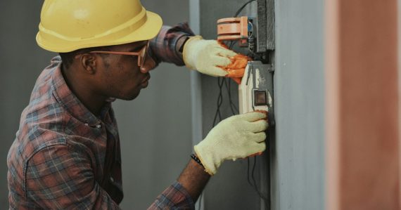 Electrician installing wiring with yellow hardhat, illustrating troubleshooting virtualized cloud environments