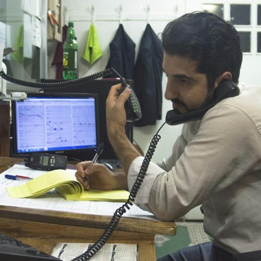 A man sitting at a desk talking on a phone, illustrating the virtues of hosted VoIP