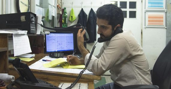 A man sitting at a desk talking on a phone, illustrating the virtues of hosted VoIP