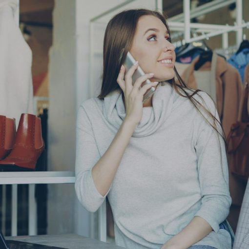Woman on the phone while looking at clothes, illustrating voice virtualization for SMBs