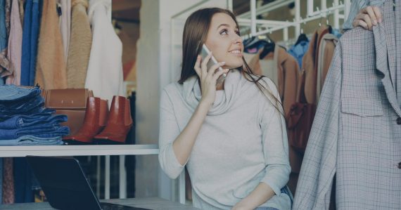 Woman on the phone while looking at clothes, illustrating voice virtualization for SMBs
