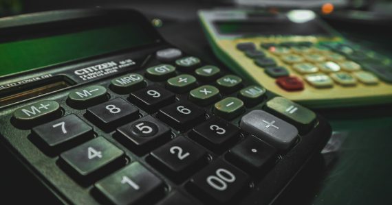 A calculator sitting on top of a table next to another calculator, illustrating VoIP cost benefits