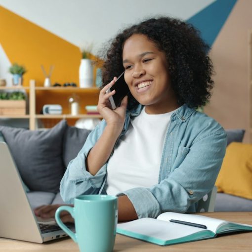 Woman talking on phone while working on laptop at desk, illustrating VoIP for small businesses