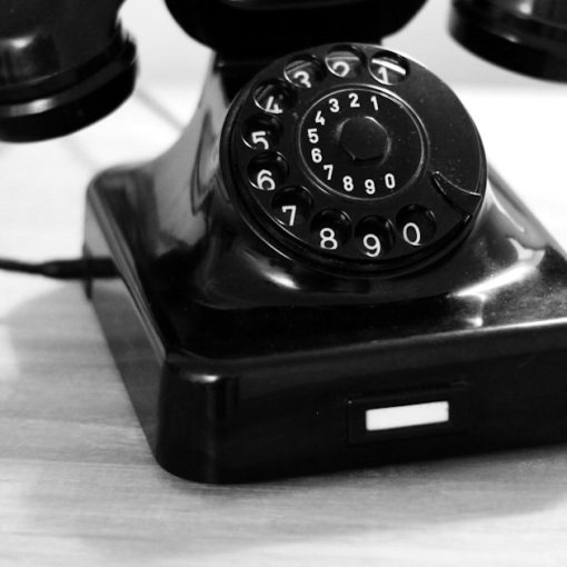 Black rotary phone on white table, illustrating VoIP replacing traditional telephony