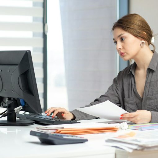 Young woman focused on computer and documents at office desk, illustrating choosing a VoIP service