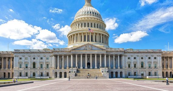 A large building with a dome and a flag on top with United States Capitol in the background, illustrating state taxes on VoIP