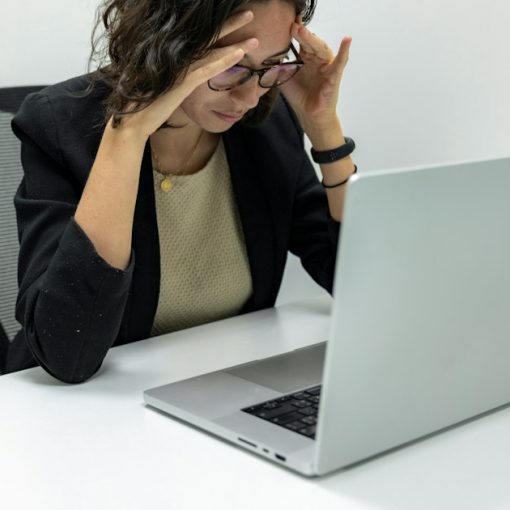 Frustrated woman with her head in her hands at a laptop, illustrating when cloud computing goes wrong