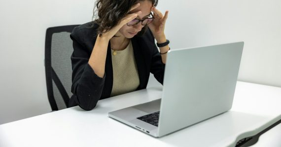 Frustrated woman with her head in her hands at a laptop, illustrating when cloud computing goes wrong
